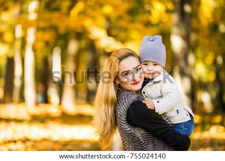 Happy young mother playing with her littlte baby son on sunshine warm autumn or summer day. Beautiful sunset light in the apple garden or in the park. Happy family concept