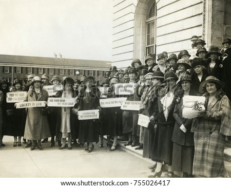 Women Suffragettes holding placards with political activist slogans in 1920. Signs read: Know Your Courts-Study Our Politicians; Liberty in Law; Law Makers Must Not Be Law Breakers; Character in Candi Royalty-Free Stock Photo #755026417