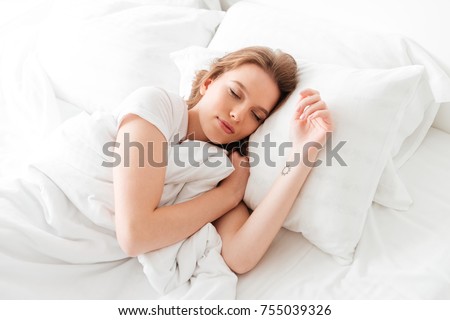 Photo of sleeping young woman lies in bed with eyes closed. Royalty-Free Stock Photo #755039326