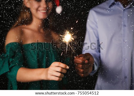 Holiday background with sparklers. Cropped shot of young friends holding bengal lights, closeup, selective focus. Birthday or winter holidays celebration, greeting card mockup