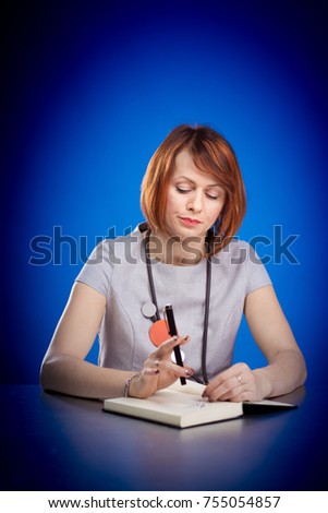 Emotional red-haired woman sitting at a table and posing against a blue background