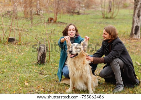 The guy is stroking the dog and the girl raised her ears in the woods for a walk