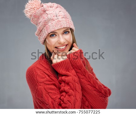 Close up face portrait of toothy smiling young woman wearing red sweater with pink knitted hat.