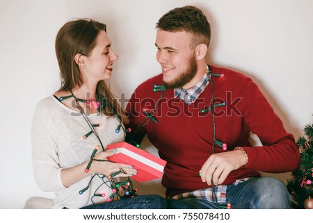 loving couple decorating Christmas tree for the holidays also exchanging gift