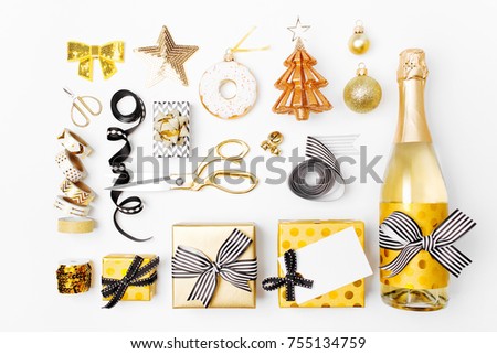 Flat Lay Christmas set with Gift boxs, Champagne bottle, Bows, Decorations and Wrapping Paper in Gold and Black colors. Flat lay, top view