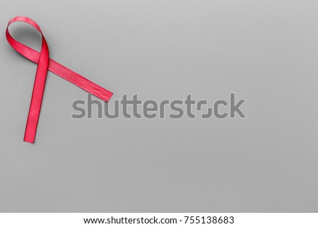 Red ribbon for HIV, AIDS, substance-abuse and anorexia awareness on grey wooden background top view copyspace