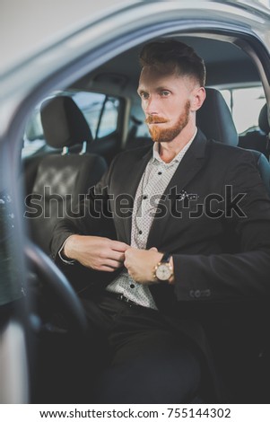 Handsome man buying new car. Auto showroom, young guy choosing car.