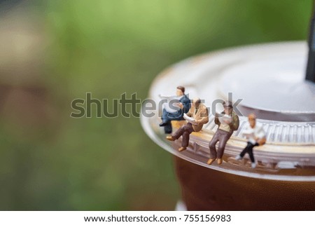 Business, Reading, relaxing, hobby concept. Group of businessman miniature mini figures sitting and read book and newspaper on a take away plastic cup iced black coffee (Americano)