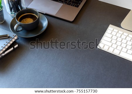 Dark Desk with laptop, eye glasses, books, pen and a cup of coffee. Top view with copy space.