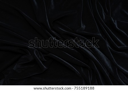 Dark black velvet fabric, wave, draperies. Beautiful textile backdrop to create creative layouts for black Friday. Close-up. Top view