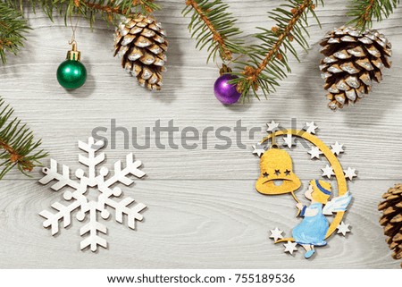 Frame from natural fir tree branches with angel, cones and other Christmas ornament on grey wooden background