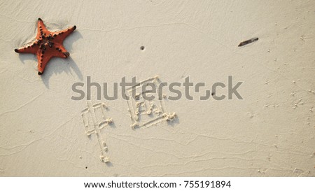 Red starfish on the beach with Chinese characters for word "China" written in the sand                     
