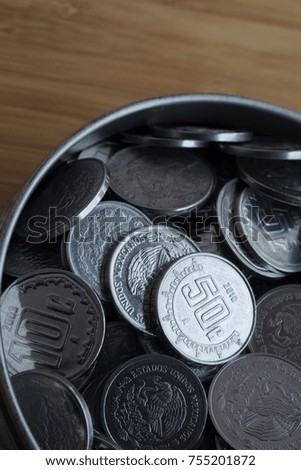 Mexican coins in a can over a wood table