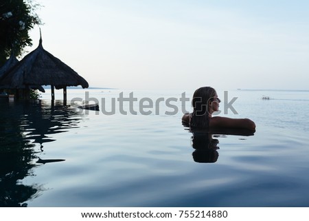 Black silhouette of happy woman on summer beach holiday relaxing in luxury spa hotel in infinity swimming pool with blue sea view. Healthy lifestyle, family travel background. Tropical island tour.