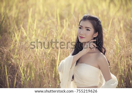 A good peasant woman dressed in a beautiful folk costume thinking in the wheat field, while harvesting in the background horizontally launched the picture.