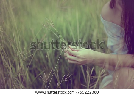 Beautiful women wearing blue dresses, hands to the grass. Alone happily