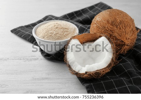 Bowl with flour and nut on wooden table