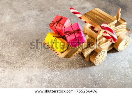 Wooden toy tractor carries Christmas presents in its bucket. The concept of a happy Christmas. Copy space. Close-up.