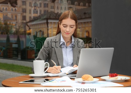 Young female marketing manager working in cafe outdoors