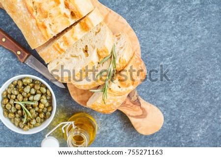 Fresh ciabatta with herbs on a dark background, top view.