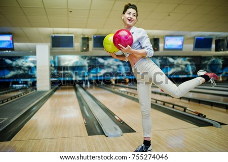 Girl with bowling ball on alley played at bowling club. 