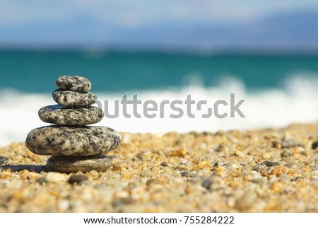 Cairn on the background of the sea, the beach and the sand. The background image for the screen saver, or for philosophical or psychological information and advertising concepts. Pyramid - balance.