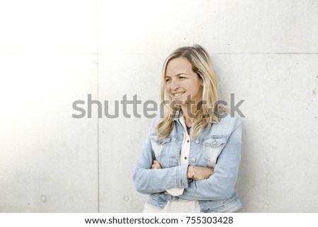 young business woman in casual look in front of a 
concrete wall