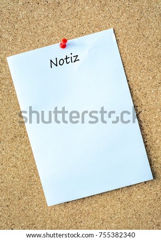 Cork wall with white piece of paper with the German word for note as a template