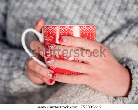 New Year's mug in female hands with beautiful New Year manicures
