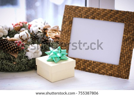 Desktop photo frame, christmas wreath and gift box on white sill against window