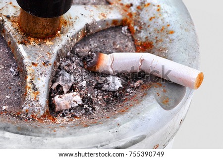 Cigarette butt left on the ashtray isolated on white background with shadow reflection. Women slim cigarette on the ashtray isolated on the white background. Slim cigarette with ash.