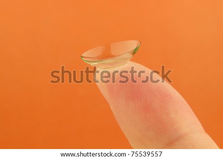 Contact lens on finger on a orange background