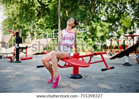 Sport girl wear on white shorts ans shirt doing exercises on simulators outdoor at park.