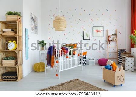 Rattan lamp above white cradle with colorful blanket in bright child's room with eco furniture