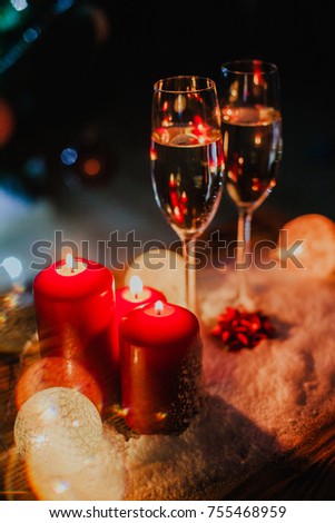 Two glasses of champagne on the background of a Christmas tree with candles in darkness with snow