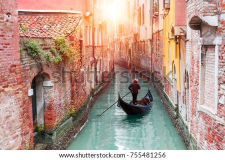 Venetian gondolier punting gondola through green canal waters of Venice Italy Royalty-Free Stock Photo #755481256