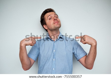 Self-satisfied and proud caucasian young man looks forward showing with index fingers on himself Royalty-Free Stock Photo #755500357