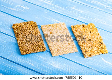 Sesame seeds, sunflower seeds and nuts in caramel glaze on the wooden rustic background.