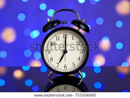 New Year's picture. Vintage alarm clock on a background of bright blurred festive lights. A bright abstract background is perfect for any design. Main background for design and text