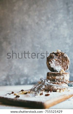 Italian castagnaccio cake made with chestnut flour, cut in disc and filled with ricotta chease,chocolate and  orange candy, is covered with iced sugar over a rusty gray background
