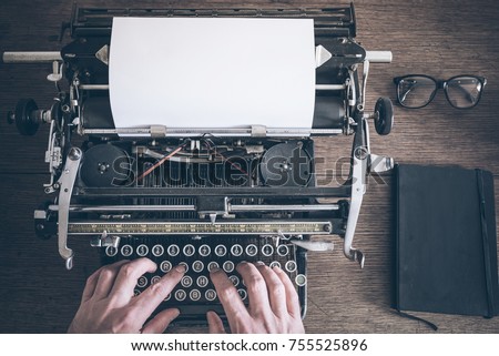 top view of man using vintage manual typewriter on rustic wooden table Royalty-Free Stock Photo #755525896
