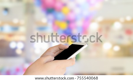 woman use mobile phone and blurred image of beautiful bokeh from the light in the mall 