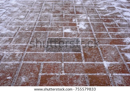Horizontal shot of paving slabs of red-brown color, covered with snow close up