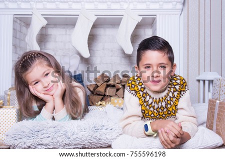 Portrait of little boy and girl. Merry Christmas and Happy Holidays concept.  Family holiday. New Year's picture of brother and sister with gifts. Children lie on the floor at home in the living room.