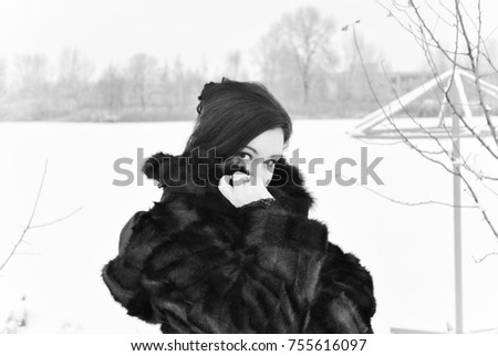 Plus size nice young lady in retro look style walk at winter time wear in not natural  fur coat. Woman have a good mood. Winter holiday time, black and white photo