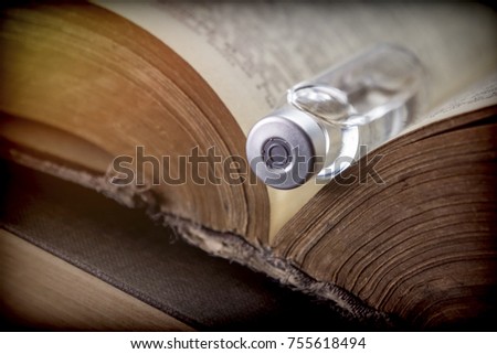 Vial on an old book of medicine, conceptual image