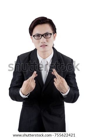 Portrait of Asian businessman wearing a formal suit while crossing his finger, isolated on white background