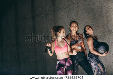 Happy young women standing together and smiling after exercising. Group of female friends relaxing after workout outdoors. Royalty-Free Stock Photo #755628706