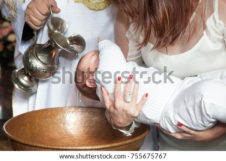 Mother holds child while priest baptizes with holy water Royalty-Free Stock Photo #755675767