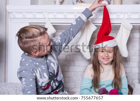 Portrait of little boy and girl. Merry Christmas and Happy Holidays concept. Family holiday. New Year's picture of brother and sister in red santa hat. Fun game and communication. 